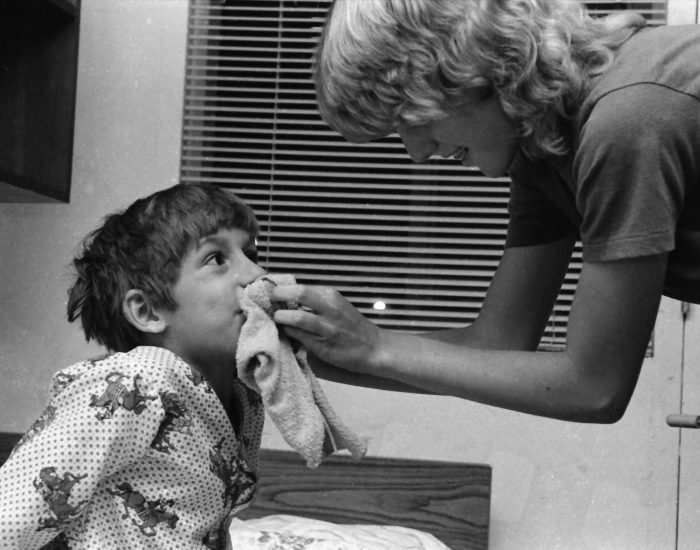 Scan000053 A camp councilor helping a young boy get ready for bed by wiping his face.