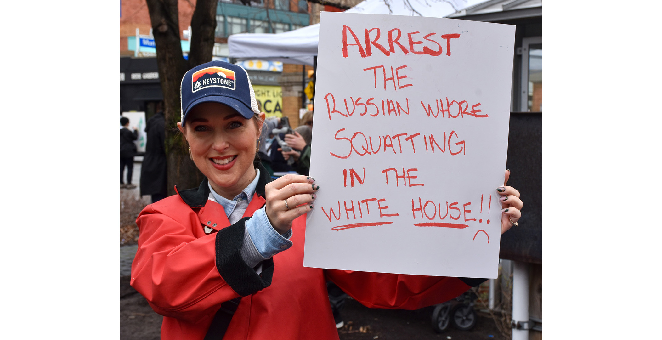 russianwhore Woman holding a sign that says "Arrest the Russian whore squatting in the White House."